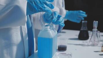 A person in a lab coat is holding a blue liquid video