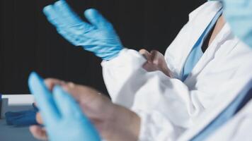 Two people in lab coats and gloves are working on a table video