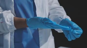A person in a lab coat is holding a pair of blue gloves video