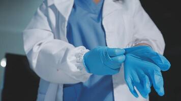 A woman in a lab coat is holding a blue glove video