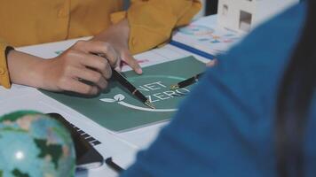 A person is writing on a green paper with a globe video