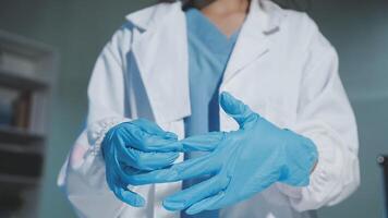 A woman in a lab coat is holding a pair of blue gloves video