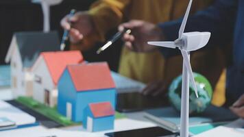 A group of people working on a model of a house with wind turbines video