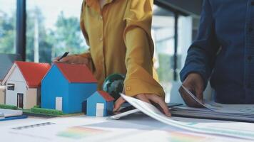 A real estate agent and a client looking at a model house video