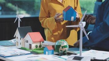 A man and woman are holding a model of a house and wind turbines video