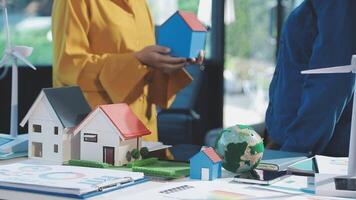 A woman is holding a model of a house and a man is holding a model of a wind video