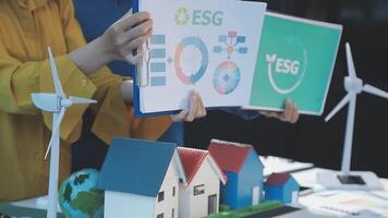 Two people holding up a paper with a house and wind turbines video