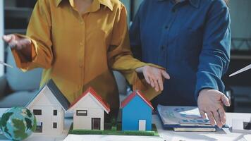 Two people are holding paper houses and a globe video