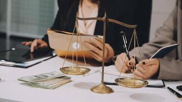 Two business people sitting at a table with money and a scale video
