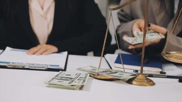 Two business people sitting at a table with money and scales video
