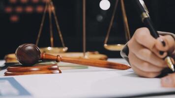 Lawyer's hand writing on paper with a pen and a gavel video