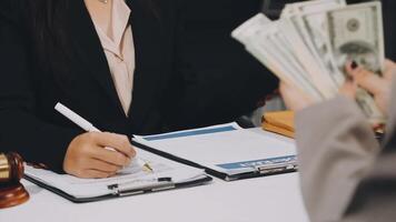 A woman in a suit is holding money while sitting at a desk video