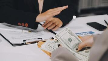 A woman handing money to another woman at a desk video