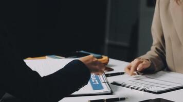 Two people sitting at a table with papers and a pen video