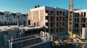 Construction site with workers, crane, and partially built multi-story building, surrounded by equipment and materials. video