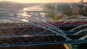 Zug Kreuzung modern Brücke Über Weichsel Fluss im Krakau, Polen, beim Sonnenuntergang mit Stadtbild im das Hintergrund. video