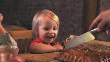 The father cuts the cake that the mother baked while the little son looks forward to trying a piece and smiles sincerely video