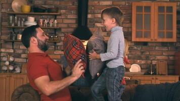 Happy father with two sons fooling around and beat each other with pillows. They are happy and laugh. The dog comes up and also gets hit by a pillow. video