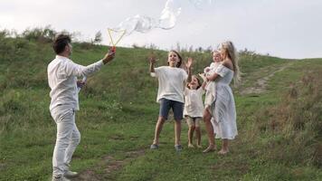 The father blows soap bubbles and the family catches them and rejoices. video