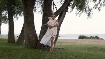 A mother and her little daughter are standing near a tree in the forest. video