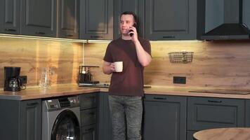 A man is talking on the phone while standing in the kitchen. video