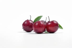 Three red cherries with leaves on a white background photo