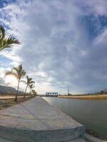 View of the dam with palm trees and blue sky in the background photo