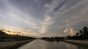 A canal with a bridge and a sunset in the background photo