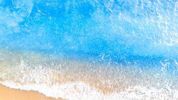 Blue sea wave on sandy beach background. Top view. Copy space photo