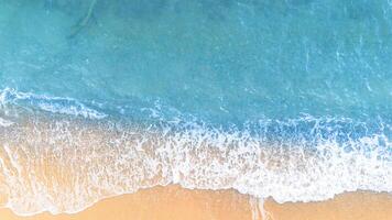 Soft wave of the sea on the sandy beach background. Top view. photo