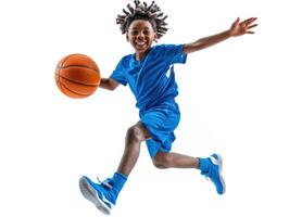 Young boy in blue athletic gear jumps while dribbling a basketball with a joyful expression indoors photo