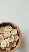 Minimalist breakfast with oatmeal and sliced bananas in wooden bowl photo