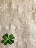 Close up of natural linen fabric with green clover leaf for eco friendly design photo