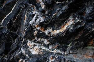 Close up of rugged rock surface with dark and light striations photo