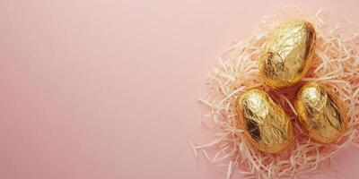 Minimalistic Easter flat lay with gold wrapped chocolate eggs on pink background photo