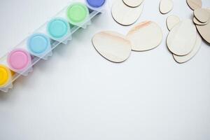 Colorful paints and wooden shapes for crafting on a white background with copy space photo