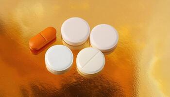 Orange and White Pills on Golden Reflective Background photo