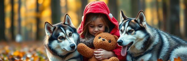 Adorable Young Girl in Red Cloak Enjoying Playtime with Two Huskies in a Peaceful Autumn Forest photo