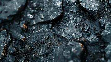 Close up view of a rugged surface covered in dark coal fragments, showcasing intricate textures and patterns under natural light, highlighting the mineral formations present. photo