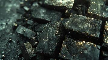 Close up view of shiny black mineral crystals scattered on a dark surface, with reflections of light creating intricate patterns in natural daylight, showcasing the beauty of geology. photo