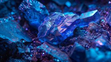 Glimmering blue crystals cluster together, their sharp edges capturing light and creating a striking visual effect. The surrounding darkness enhances their vibrant hues, revealing intricate patterns. photo