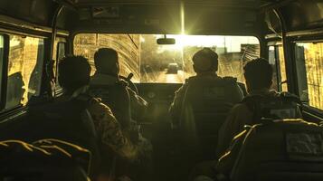 Four soldiers sit in a military vehicle, facing forward as the sun sets in the background, casting warm light and shadows inside the vehicle. photo