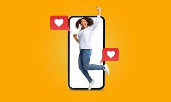 A person joyfully jumps in front of a large smartphone, surrounded by heart-shaped message icons. This vibrant expression captures the excitement of connecting through social media. photo