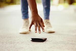 Closeup view of black guy picking up lost wallet on city street photo
