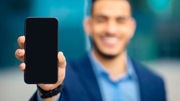 Modern technologies and business concept. Unrecognizable businessman showing smartphone with empty screen, recommending brand new mobile application for business, finance, selective focus photo