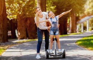 Joyful Mother And Daughter Riding Segway Having Fun In Park Outside. Family Weekend Adventure photo