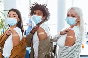 After Vaccination Concept. Portrait Of Happy Vaccinated People In Mask Showing Arm With Sticking Patch Getting Antiviral Injection, Sitting In Line With Rolled Up Sleeve. Healthcare photo
