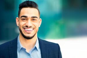Business people concept. Closeup portrait of happy middle-eastern young businessman posing over modern business center, cheerful handsome bearded arabic man in suit smiling at camera photo