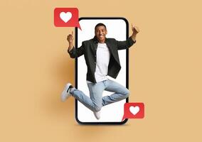 A joyful individual jumps in excitement, emerging from a smartphone screen. The phone displays love symbols with text notifications. This highlights modern expressions of affection and connection. photo