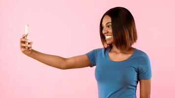 Cheerful Black Female Making Selfie On Smartphone Posing And Having Fun Over Yellow Studio Background. Social Media, Blogging. Mobile Application For Self-Portraits Concept. Panorama, Side View photo